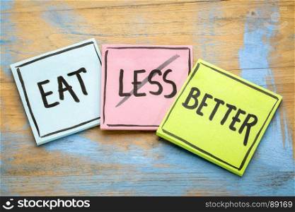 eat better (not less) - healthy eathing concept - handwriting on sticky notes against grunge wood