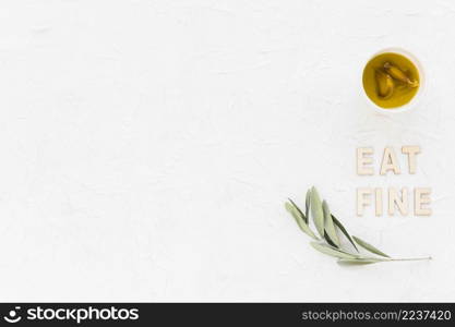 eat fine text with olive twig garlic clove oil bowl white backdrop