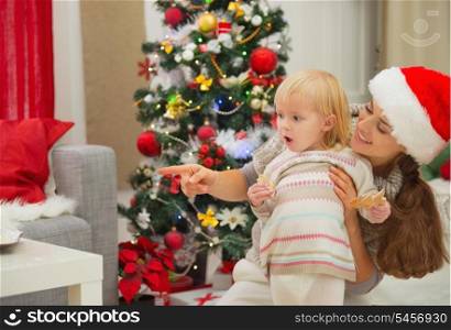 Eat smeared baby and mother near Christmas tree looking on copy space