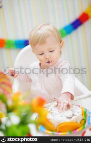 Eat smeared baby touching birthday cake