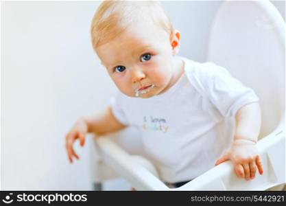 Eat smeared pretty baby girl in baby chair eating &#xA;