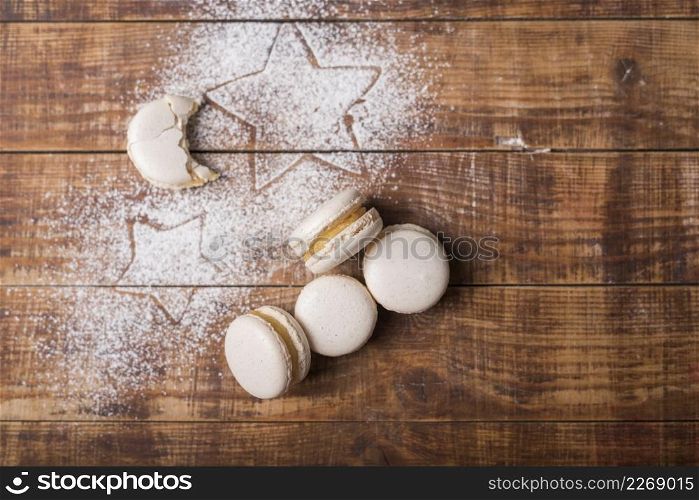 eaten moon shape macaroons with star shape sugar powder wooden surface