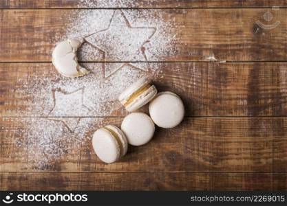 eaten moon shape macaroons with star shape sugar powder wooden surface