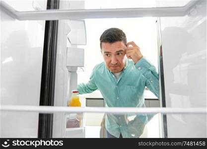 eating and diet concept - middle-aged man looking for food in empty fridge at kitchen. man looking for food in empty fridge at kitchen
