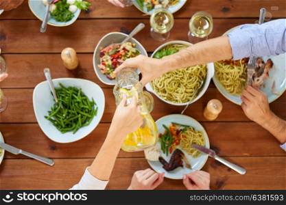 eating and leisure concept - group of people having dinner and drinking water at table with food. people at table with food eating and drinking