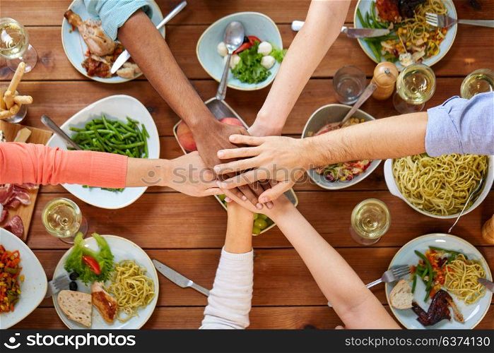 eating and leisure concept - group of people having dinner and holding hands together over table with food. people holding hands together over table with food
