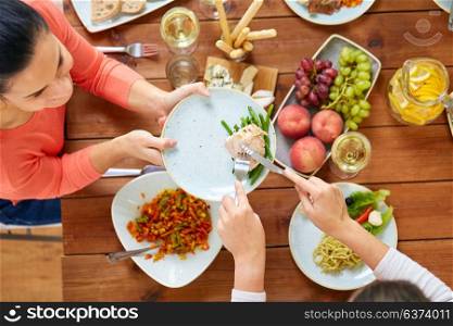 eating and leisure concept - women having roast chicken or turkey for dinner at table with food. women eating chicken for dinner