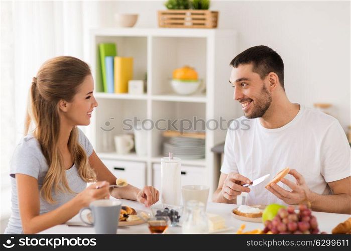 eating and people concept - happy couple having breakfast at home. happy couple having breakfast at home