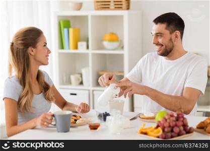 eating and people concept - happy couple having breakfast at home. happy couple having breakfast at home