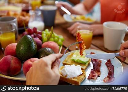 eating and people concept - male hands with knife and bacon on fork at table full of food. hands with bacon on fork at table full of food