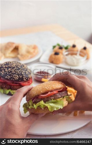Eating burger. Delicious hamburger in the male hands. Fastfood unhealthy meal.. Fastfood unhealthy meal.