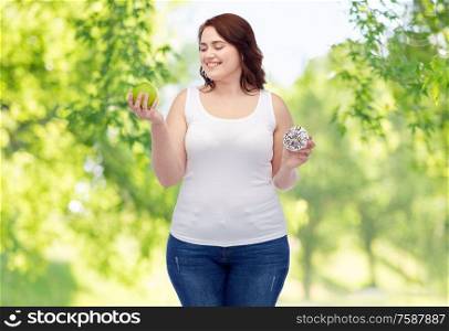 eating, food and diet concept - happy smiling plus size woman choosing between apple and donut over green natural background. plus size woman choosing between apple and donut
