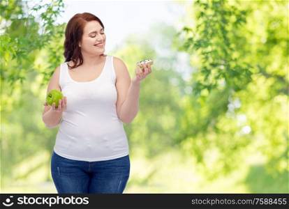 eating, food and diet concept - happy smiling plus size woman choosing between apple and donut over green natural background. plus size woman choosing between apple and donut