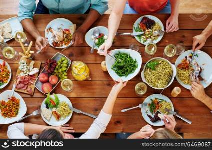 eating, food and leisure concept - group of people sharing green beans at table. group of people eating at table with food