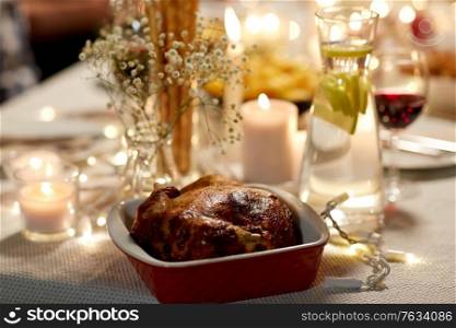 eating, holiday and food concept - roast chicken in baking dish on served table at home dinner party. roast chicken on served table at home dinner party