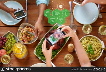 eating, people and technology concept - hands with smartphones photographing food on table over nutritional value chart. hands with smartphones and food on table