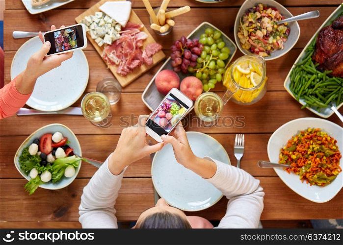 eating, people and technology concept - people with smartphones photographing food on table. people with smartphones photographing food