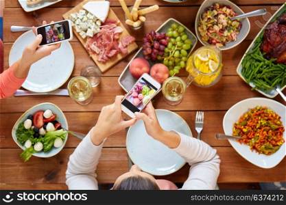 eating, people and technology concept - people with smartphones photographing food on table. people with smartphones photographing food