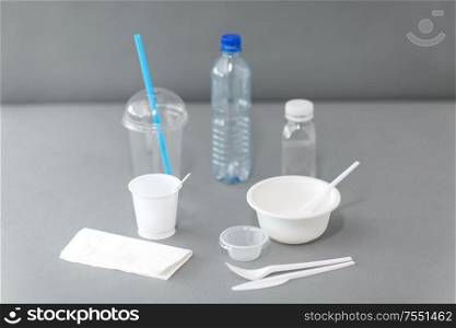 eating, recycling and ecology concept - disposable plastic dishes on grey background. disposable plastic dishes on table