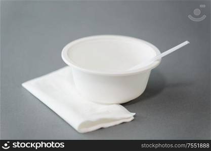 eating, recycling and ecology concept - white disposable plastic plate with spoon and paper napkin on grey background. disposable plastic plate with spoon and napkin