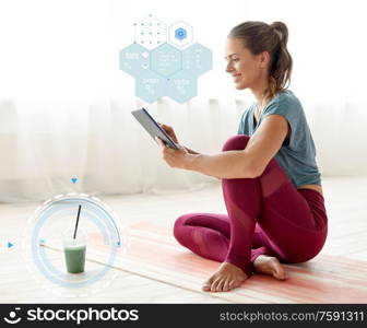 eating, technology and healthy lifestyle concept - woman with tablet pc computer and cup of smoothie at yoga studio over food nutritional value chart. woman with tablet pc and drink at yoga studio