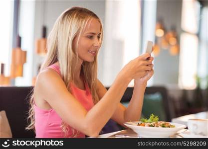 eating, technology, communication and leisure concept - happy woman with smartphone and salad for lunch at restaurant. happy woman with smartphone eating at restaurant