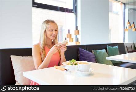 eating, technology, communication and leisure concept - happy woman with smartphone, salad and coffee for lunch at restaurant. happy woman with smartphone eating at restaurant