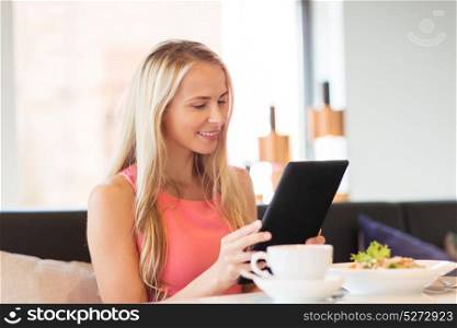 eating, technology, people and leisure concept - happy young woman with tablet pc computer and food at restaurant. happy young woman with tablet pc at restaurant