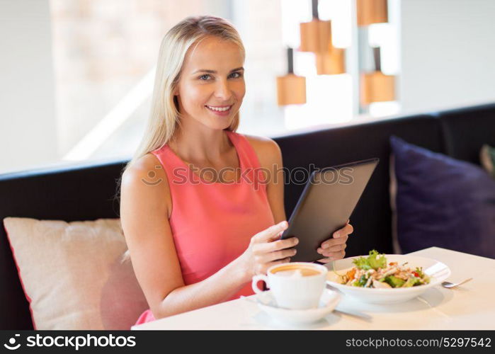 eating, technology, people and leisure concept - happy young woman with tablet pc computer and food at restaurant. happy young woman with tablet pc at restaurant