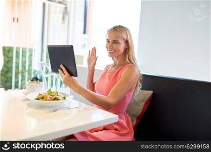 eating, technology, people and leisure concept - happy young woman with tablet pc computer and food having video conference at restaurant. happy young woman with tablet pc at restaurant