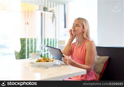 eating, technology, people and leisure concept - happy young woman with tablet pc computer, earphones and food at restaurant. happy young woman with tablet pc at restaurant
