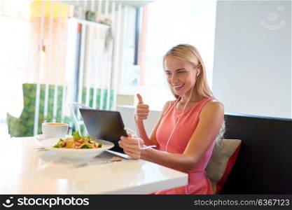 eating, technology, people and leisure concept - happy young woman with tablet pc computer and food having video conference at restaurant. happy young woman with tablet pc at restaurant