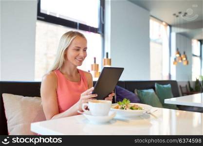 eating, technology, people and leisure concept - happy young woman with tablet pc computer and food at restaurant. happy young woman with tablet pc at restaurant