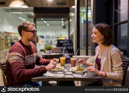 eating, vegetarian food and people concept - happy couple or friends having dinner at vegan restaurant. happy couple eating dinner at vegan restaurant