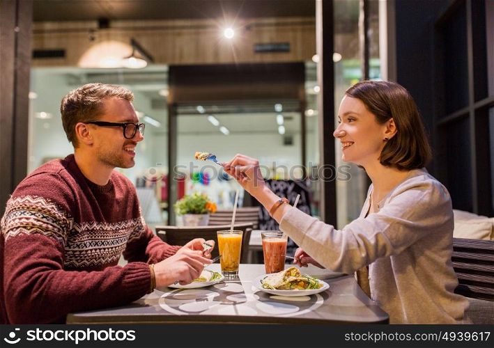 eating, vegetarian food and people concept - happy couple or friends having dinner at vegan restaurant. happy couple eating dinner at vegan restaurant