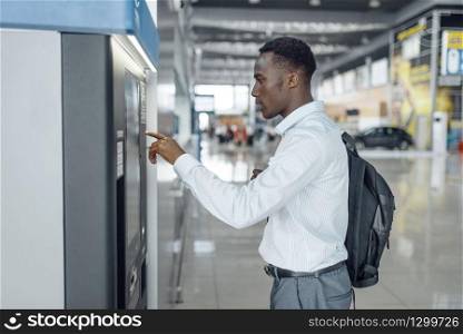 Ebony businessman at coffee machine in car dealership. Successful business person on motor show, black man in formal wear, automobile showroom