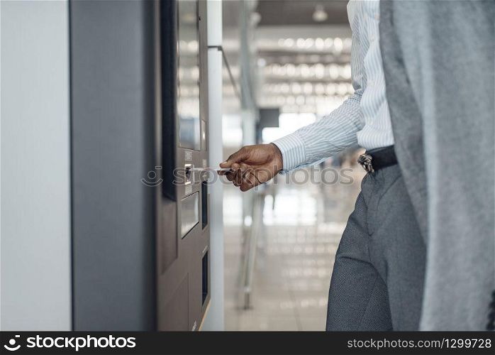 Ebony businessman at coffee machine in car dealership. Successful business person on motor show, black man in formal wear, automobile showroom. Businessman at coffee machine in car dealership