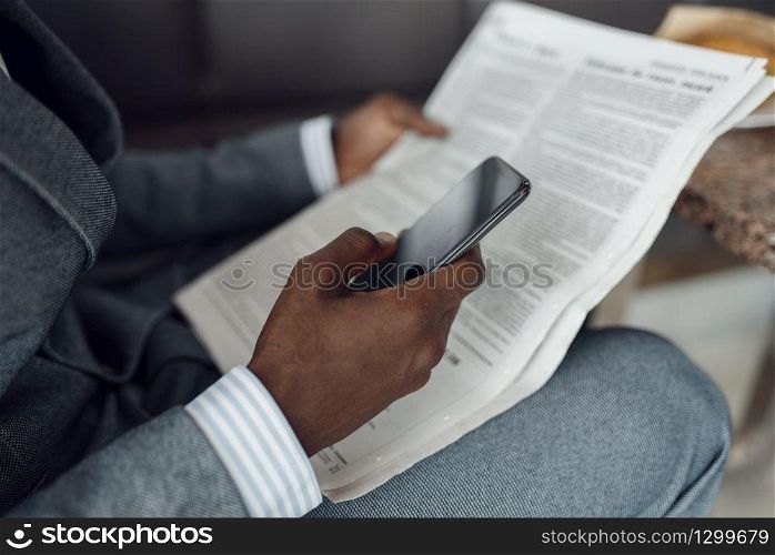 Ebony businessman hands with newspaper and phone. Successful business person, black man in formal wear