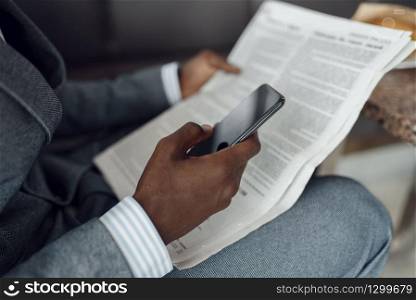 Ebony businessman hands with newspaper and phone. Successful business person, black man in formal wear