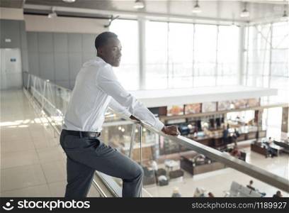 Ebony businessman looking on food-court in mall. Successful business person, black man in formal wear, shopping center