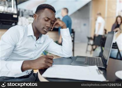 Ebony businessman working on laptop in office. Successful business person at his workplace, black man in formal wear
