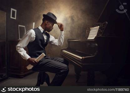 Ebony grand piano player, jazz musician. Negro performer poses at musical instrument before playing melody