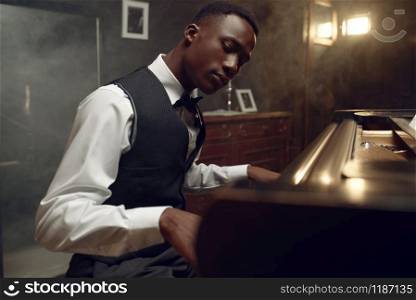 Ebony grand piano player, jazz performance in club. Negro performer poses at musical instrument before playing melody. Ebony grand piano player, jazz performance
