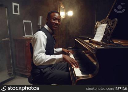 Ebony grand piano player, jazz performance in club. Negro performer poses at musical instrument before playing melody