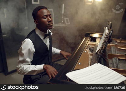 Ebony grand piano player performing classical music. Negro performer poses at musical instrument, jazz musician