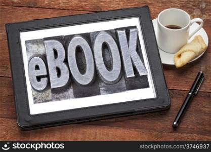 ebook (electronic book) - a word in grunge letterpress metal type on a digital tablet with a cup of coffee