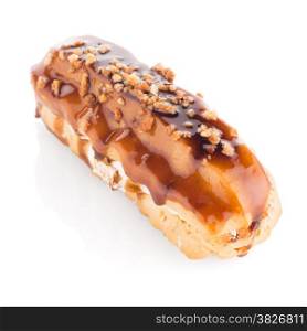 Eclair with caramel decoration on white reflective background.