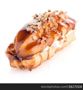 Eclair with caramel decoration on white reflective background.