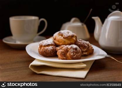 eclairs with custard cream with tea and teapot