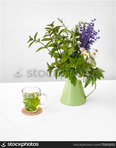 eco and organic concept - herbal tea and flowers in green jug on on white background. herbal tea and flowers in jug